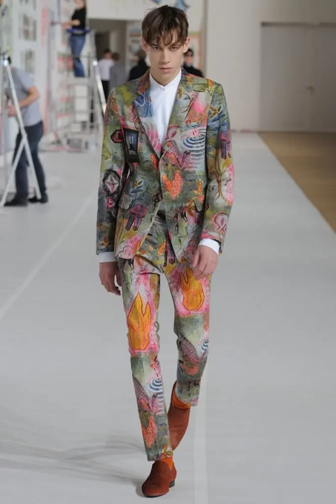 Male model wearing a bold, multicoloured printed suit with red shoes
