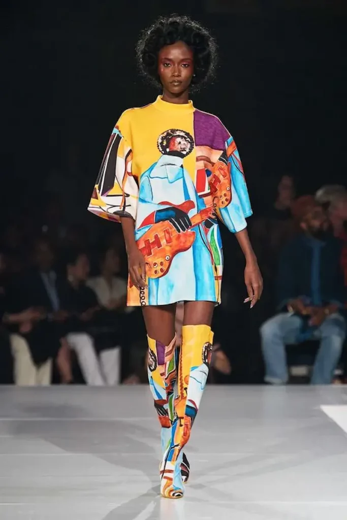 Runway model in colourful, graphic-print dress and matching boots