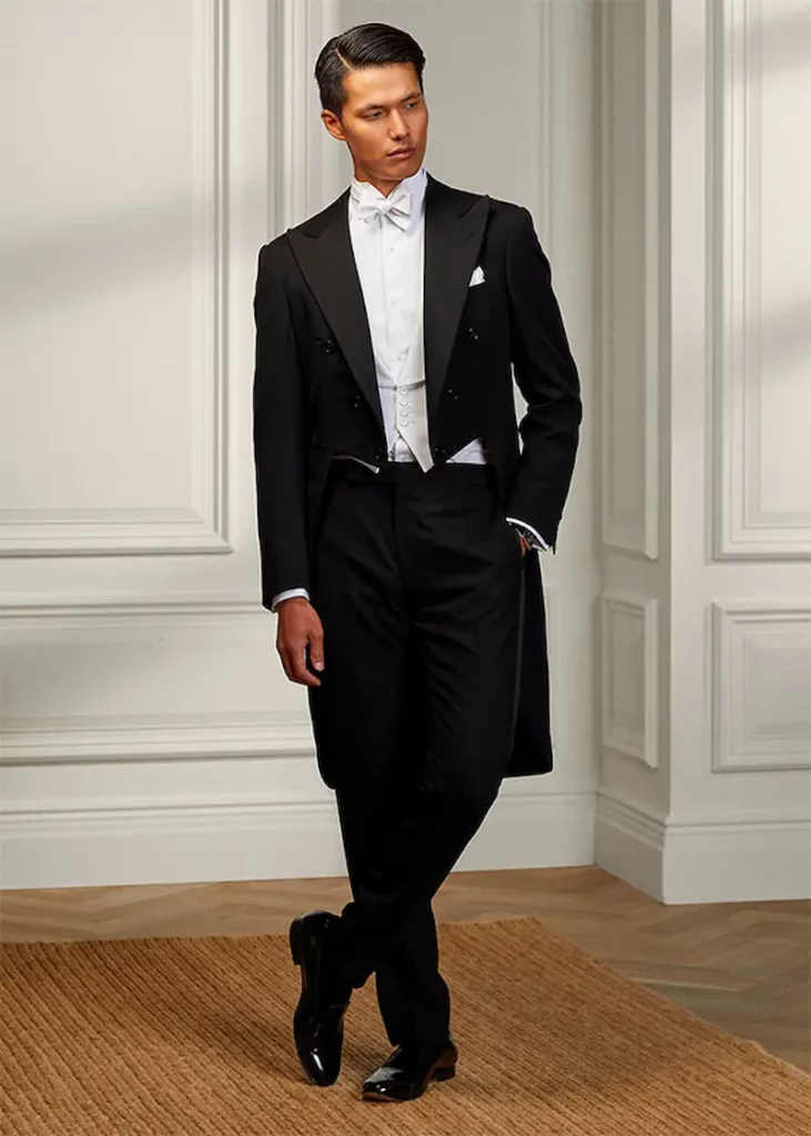 Man dressed in traditional white attire with tailcoat, white bow tie, and formal trousers